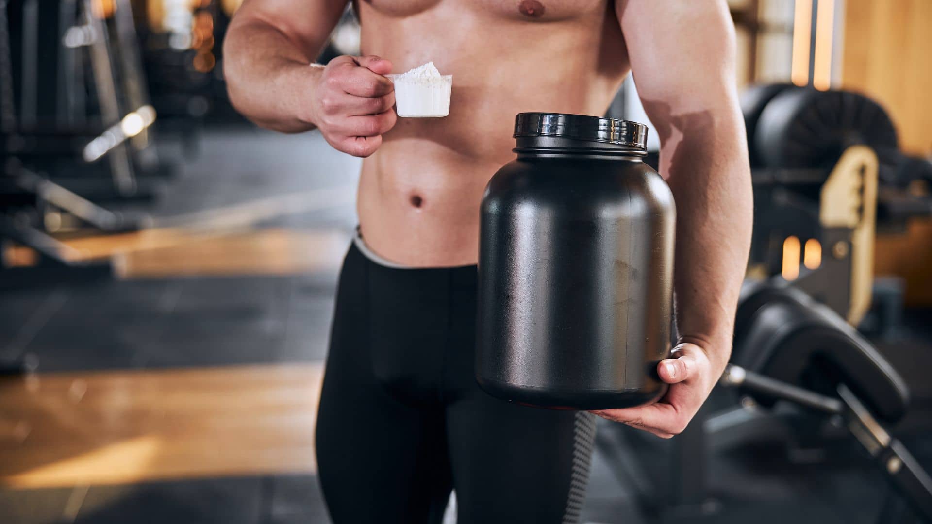 Bodybuilder taking sportduring workout in gym supplements