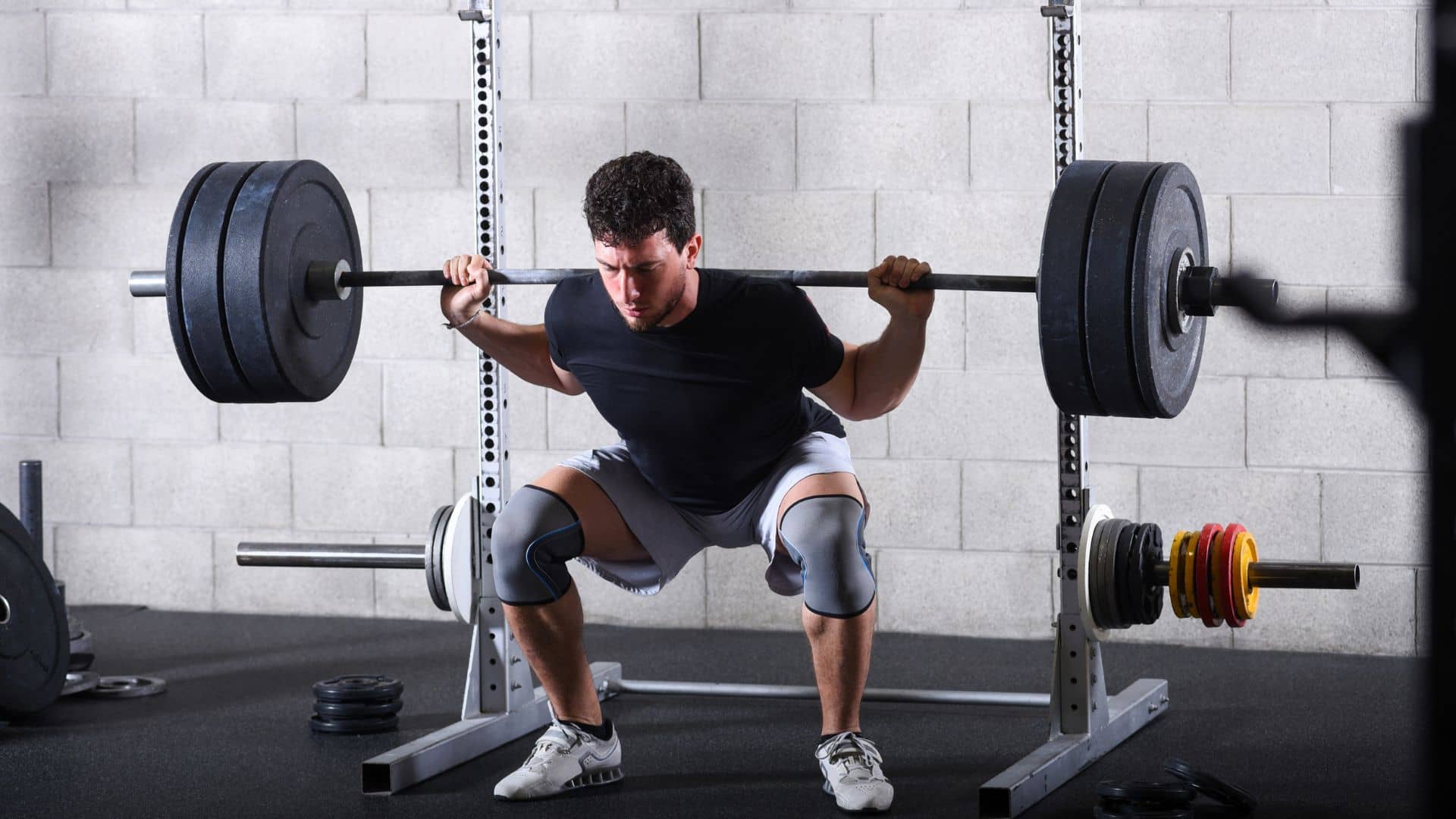 Young Man Performing Heavy Back Squats in Gym