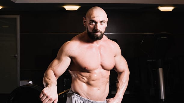 bald-man-posing-near-barbell..