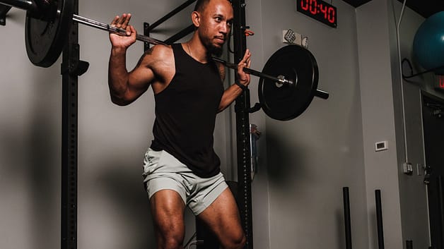 A Man in a Tank Top Carrying a Barbel