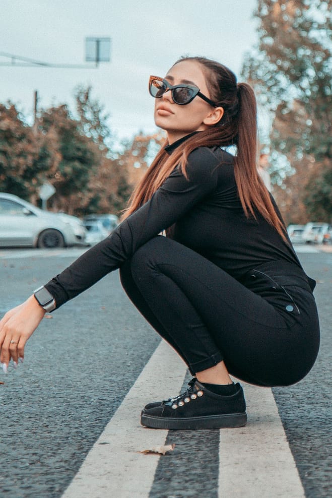 A slav Woman in a Black Outfit Squatting on a Road