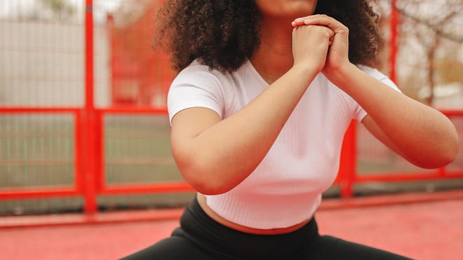 Woman in White Shirt Doing Squats Outdoors