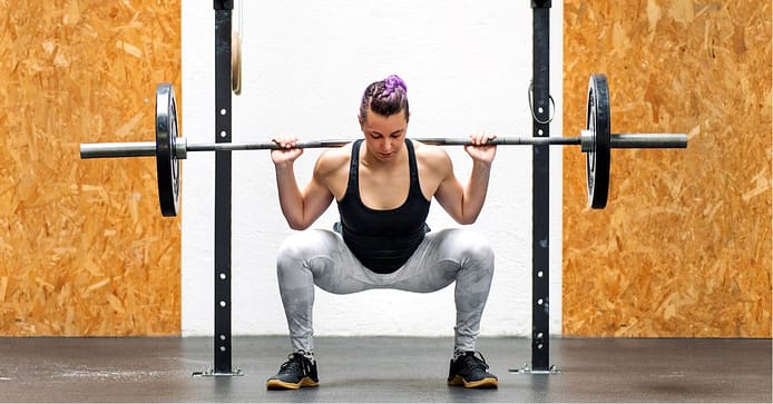 Young girl doing a back squat with a barbell