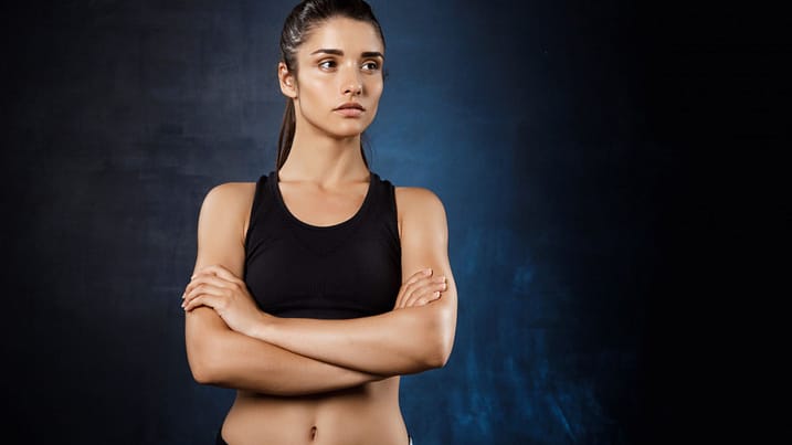 beautiful-sportive-girl-posing-with-crossed-arms-dark-wall ....