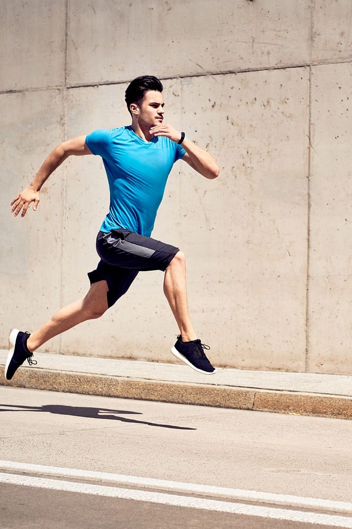 Health and fitness concept. Man doing sprinting and jumping exercises during workout session in the city