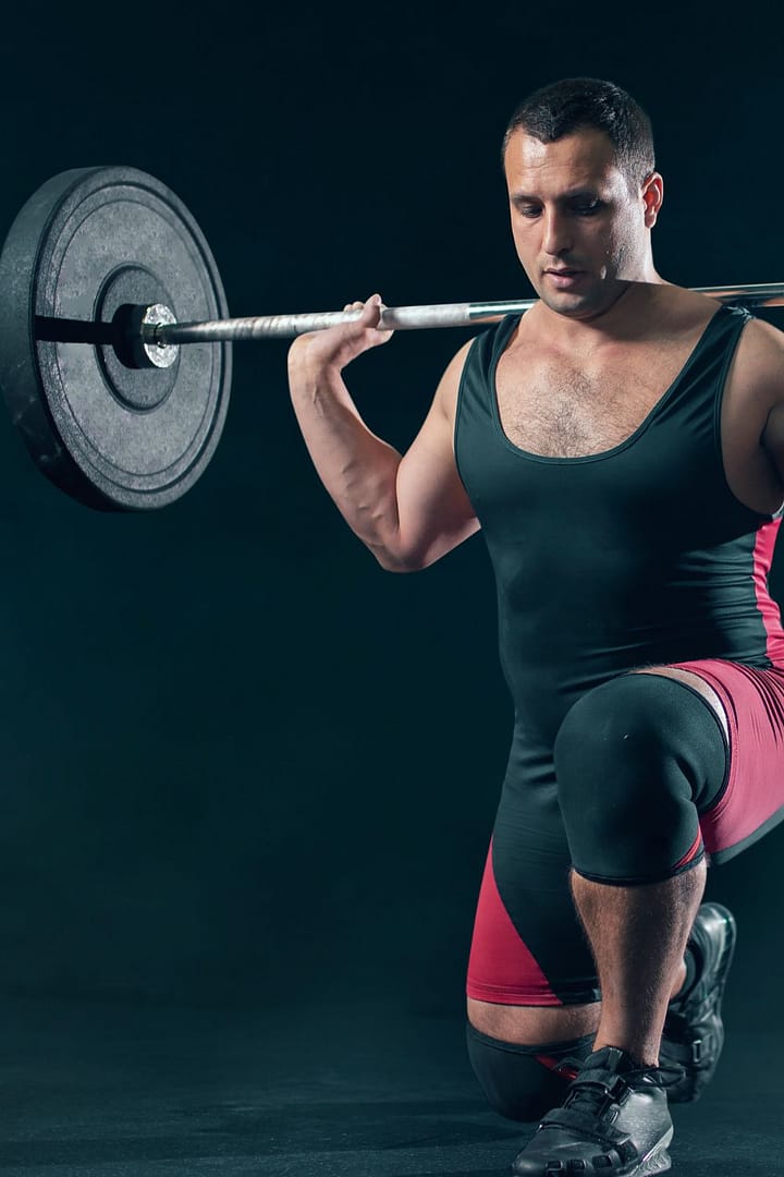 Weight Lifter Doing Squats with a Barbell in Gym