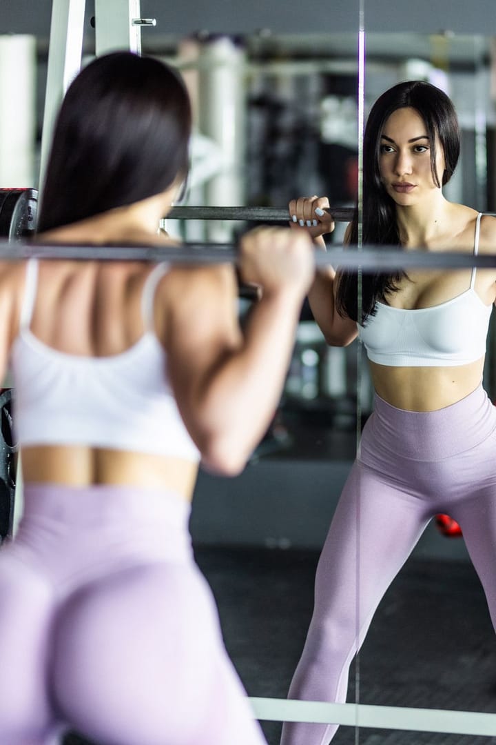 Attractive young sports woman with barbell. Doing squats. Beautiful girl squatting.(opens in a new tab or window)