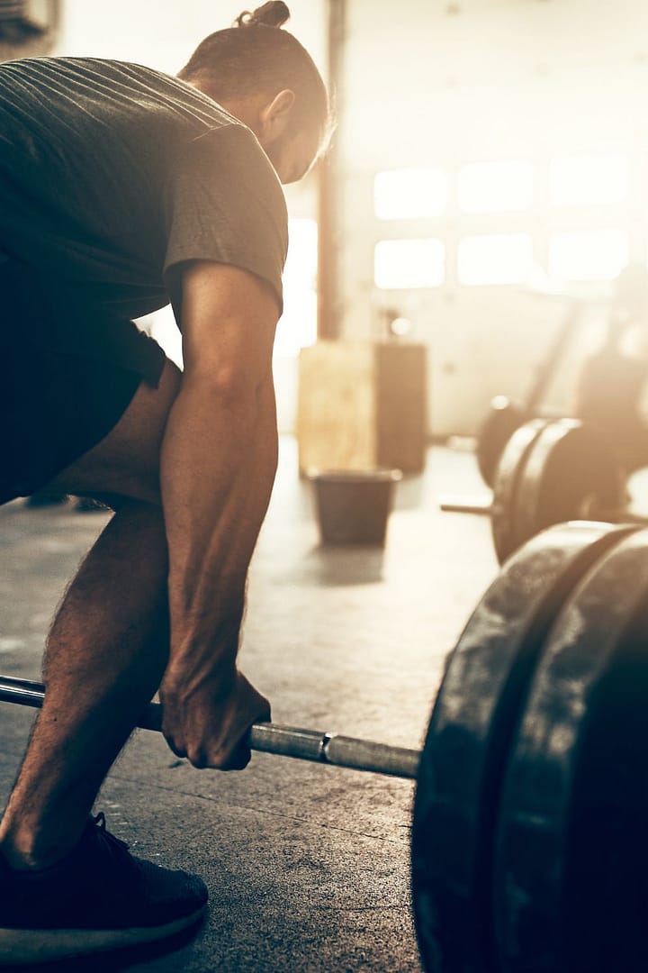 Fit Young Man Lifting Heavy Weights with a Gym Partner