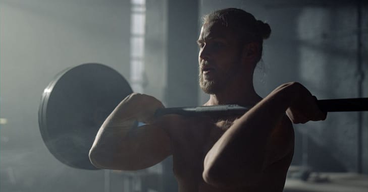 Powerlifter lifting weights during workout. Guy doing front squat with barbell