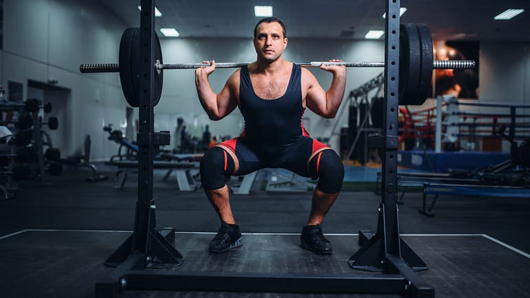 Powerlifter Doing Squats with Barbell in Gym